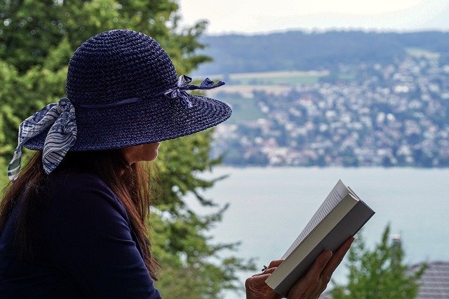 woman reading book by lake